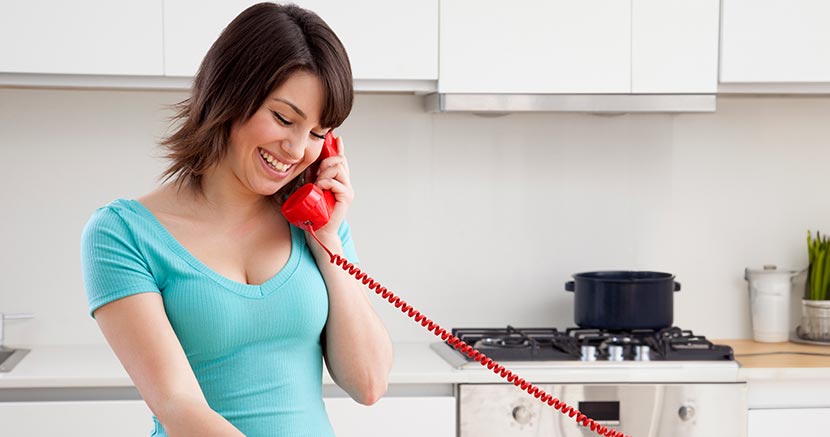 Mujer joven hablando por el teléfono de casa