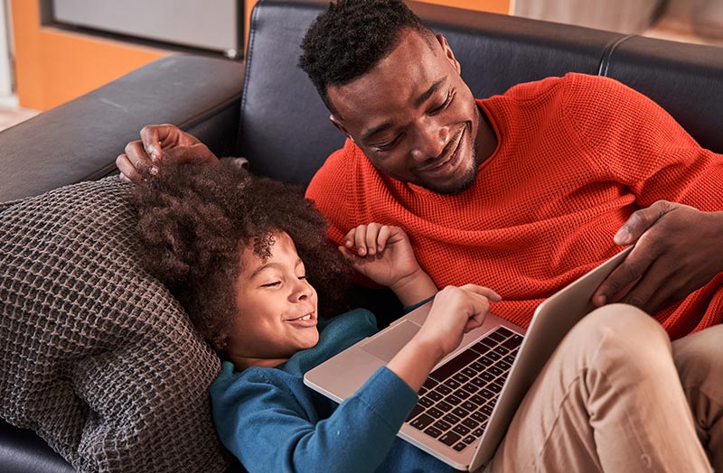 Father and son laughing whiile using laptop