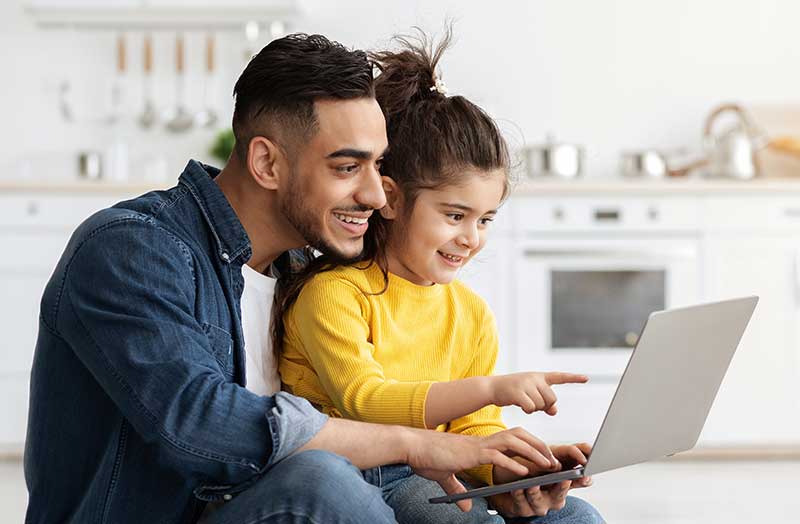 Father and son laughing whiile using laptop